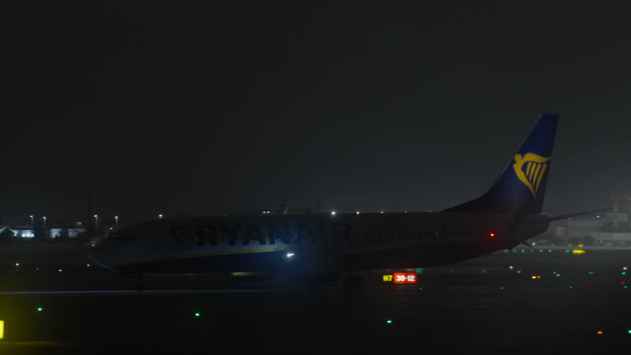 夜の空港滑走路をタキシングする民間航空機