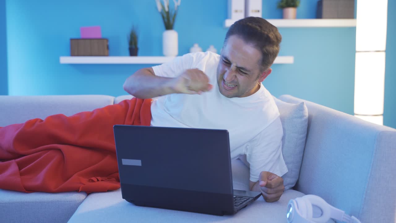 hombre usando computadora portátil mientras está acostado cierra la computadora portátil nerviosamente.