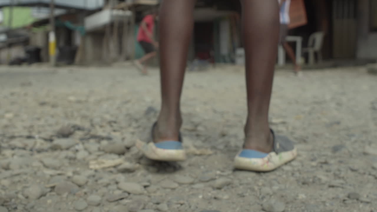 Feet of children playing football on the street of poor neighborhood in Buenaventura in Colombia
