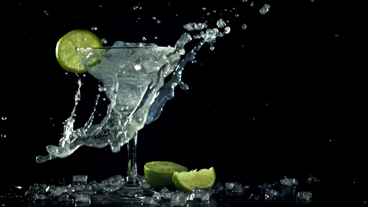 Movimento rallentato di ghiaccio che schizza in un bicchiere da Margarita con lime