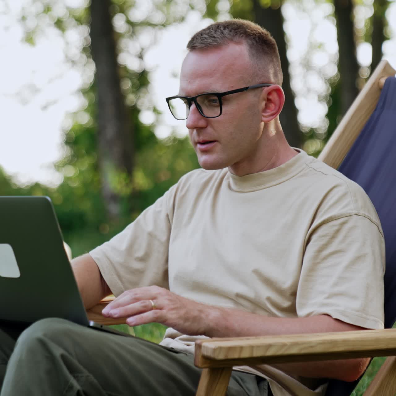 Busy man working remote in nature. Freelancer in glasses focused on work having some difficulties