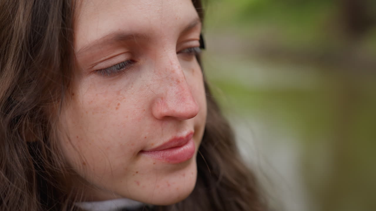 white woman closeup contemplative portrait by river, poet reflecting with soft freckles and gentle smile, natural softlight and bokeh background, subtle skin texture, calm hopeful expression, outdoor