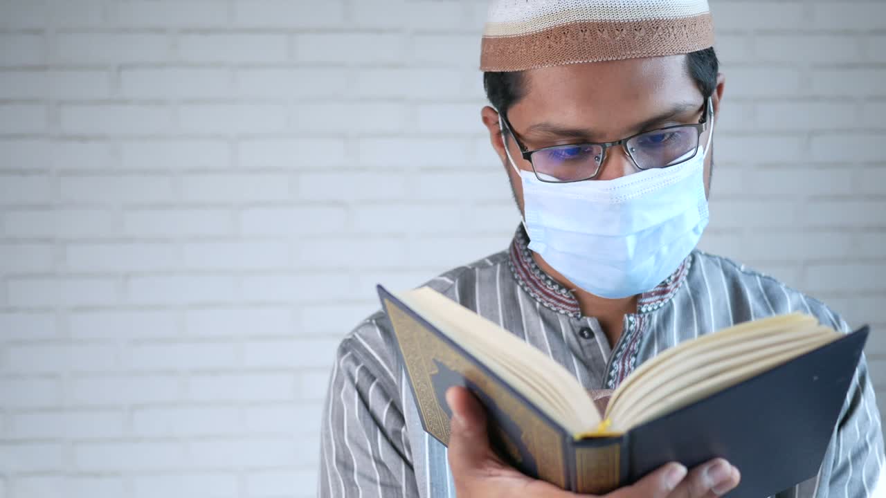 Pria Muslim bermasker membaca kitab suci Al-Qur'an