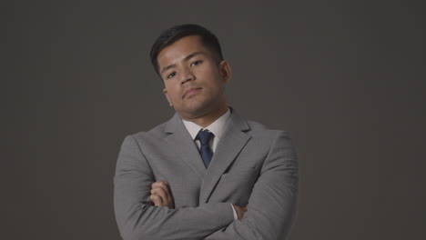 studio portrait of serious businessman in suit against grey background looking at camera