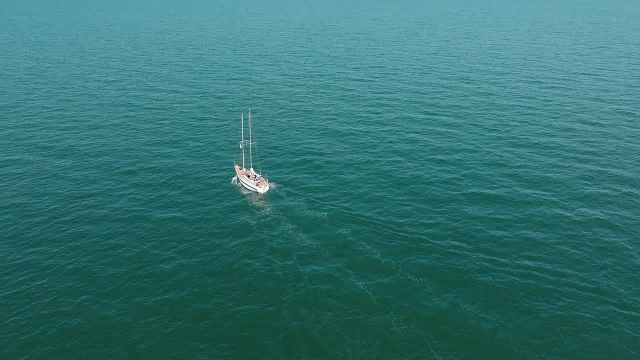 vista aérea de un velero blanco en el tranquilo mar báltico, yate de vela blanco en medio del mar sin límites, día soleado de verano, disparo amplio avanzando, inclinándose hacia abajo