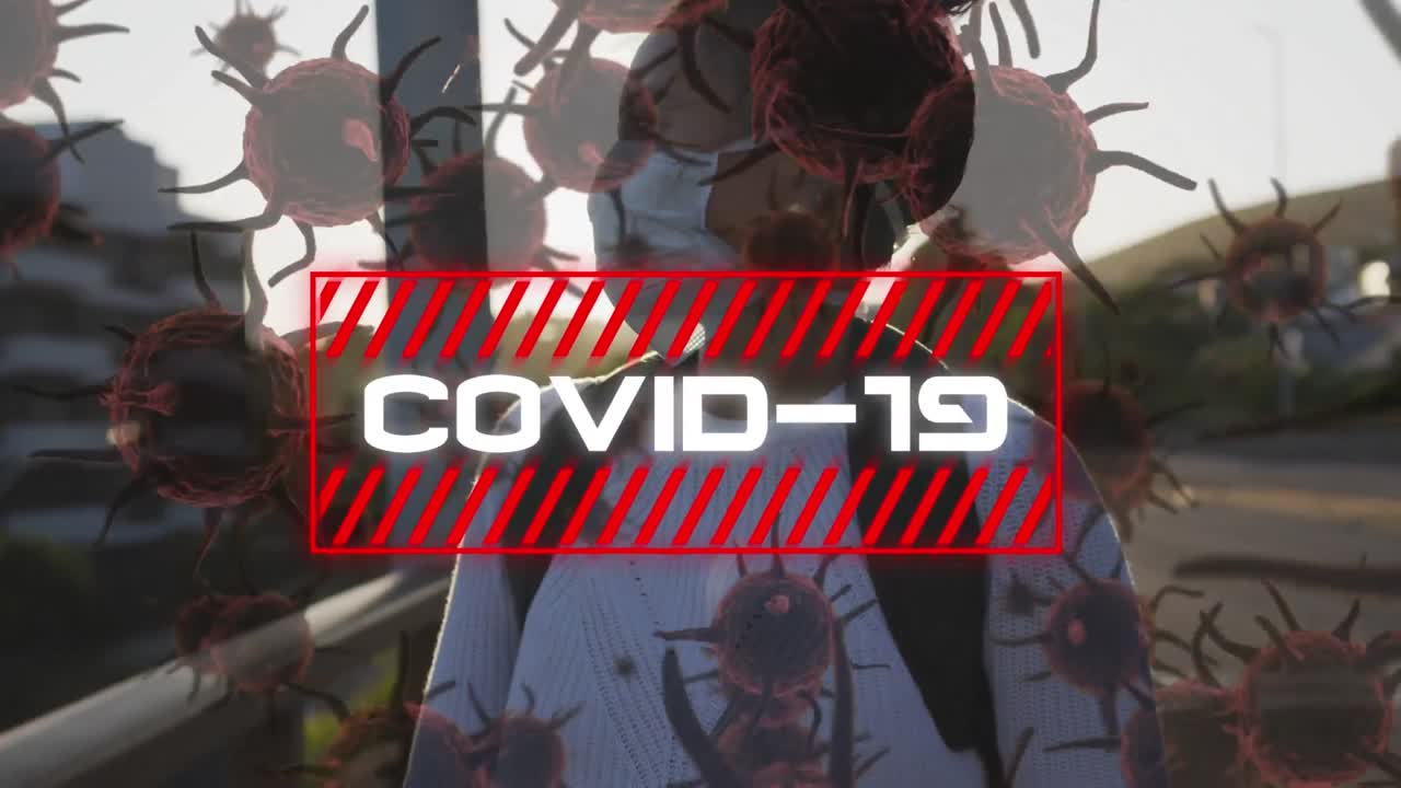 Animation of the word Covid-19 written in white letters over a woman wearing a mask in the street