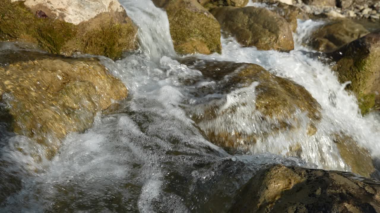 Ripresa al rallentatore dell'acqua che scorre sulle rocce nelle Alpi svizzere, vicino a Walensee. La dolce cascata crea una scena rilassante e pacifica, mostrando la bellezza naturale e la tranquillità del paesaggio alpino.
