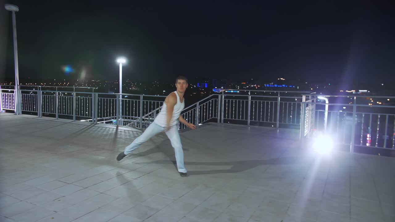 Uomo che balla su un tetto di notte