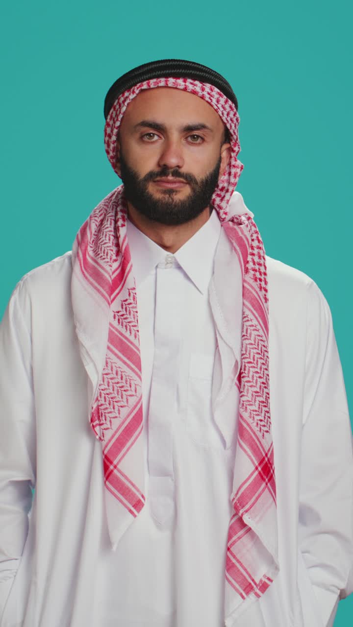 Pystysuuntainen video muslimimiehestä nyökkäämässä studiossa kuvattuna