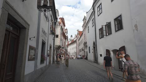 historic český krumlov street with white buildings and iron signs under a bright blue sky in czech republic