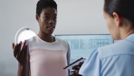 Two-diverse-businesswoman-working-and-talking-in-office