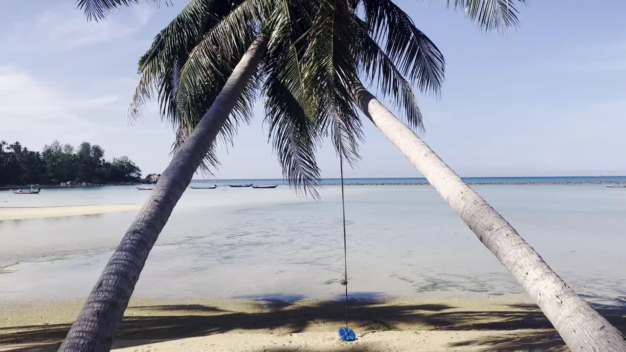 Vista panorâmica de uma praia tropical em Koh Phangan, Tailândia, com águas claras e palmeiras balançando com a brisa.