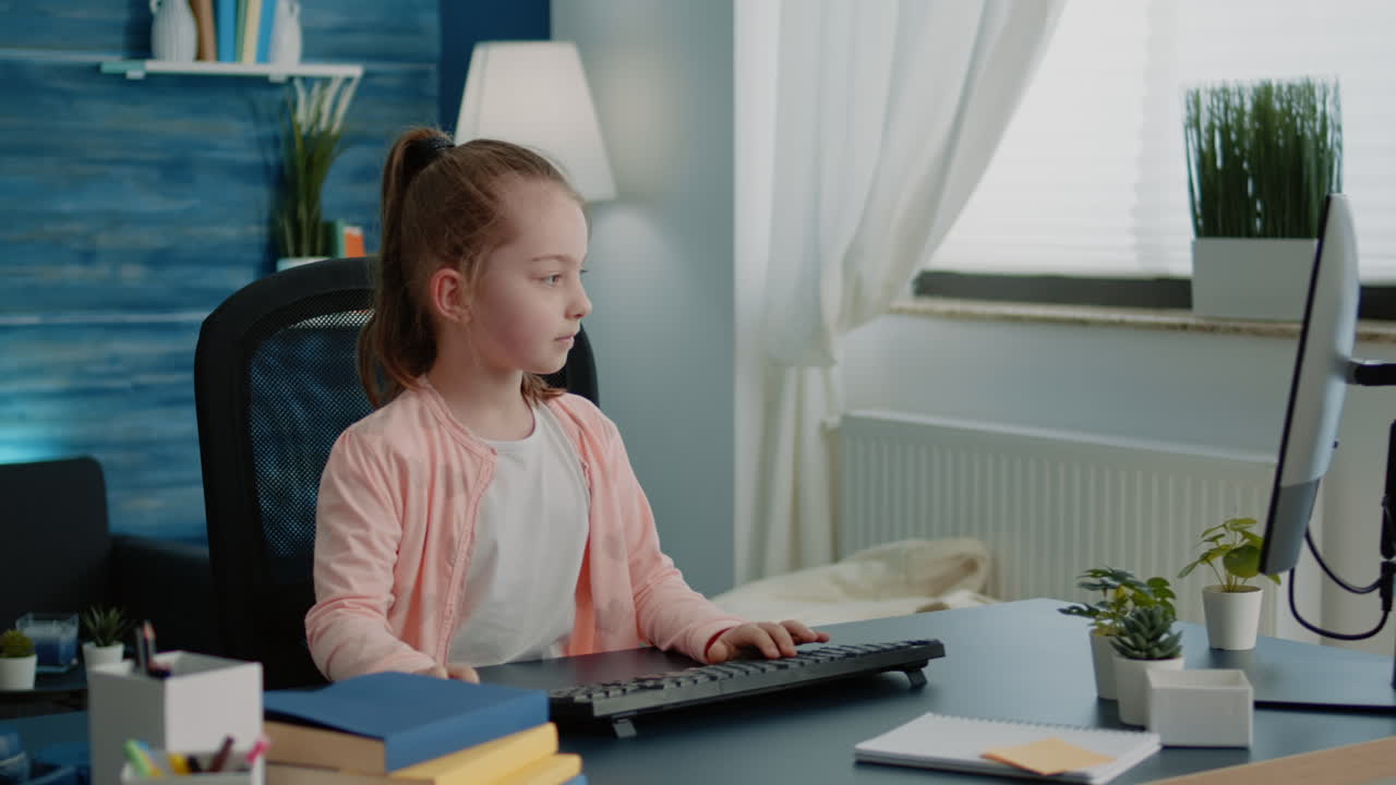 Little girl sitting at desk using computer and keyboard