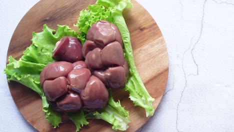 raw chicken gizzards on a wooden board