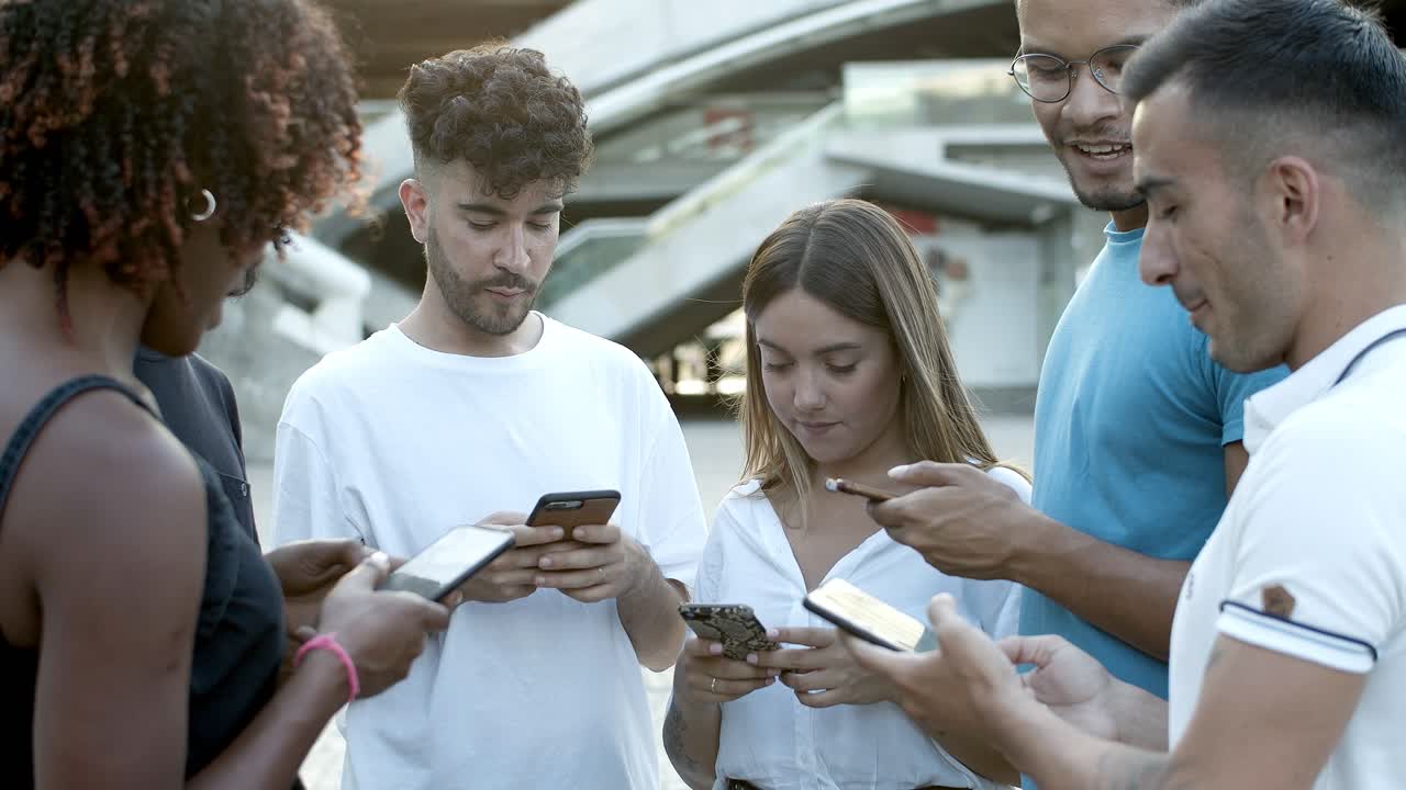 amigos alegres de pie en círculo en la plaza con teléfonos