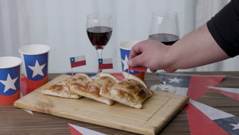 fiestas patrias chile poniendo una bandera chilena en empanada y banderas chilenas y copas de vino