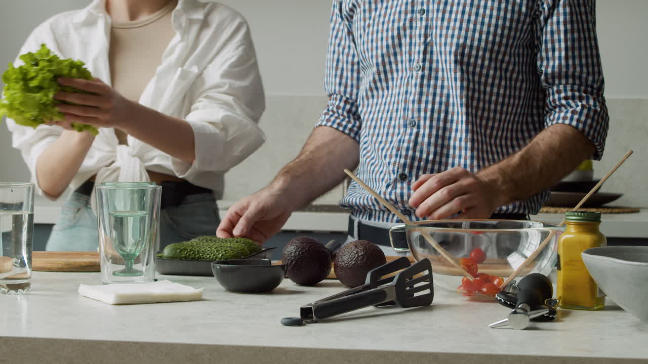 крупным планом молодая пара готовит еду на современной кухне