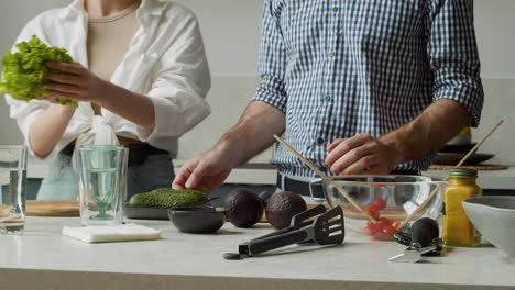 primo piano di una giovane coppia che prepara il cibo in una cucina moderna