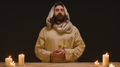 studio shot of man wearing robes representing figure of jesus christ holding wooden cross 2