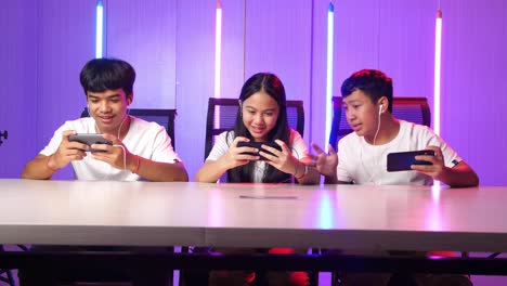 team of asian esport gamers playing in competitive video games on a cyber games tournament by mobile phone