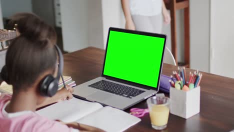 Biracial-schoolgirl-having-class-on-laptop-video-call-with-copy-space-in-slow-motion