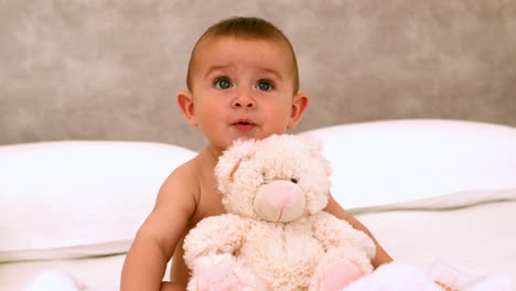 cute baby on a bed with teddy bear