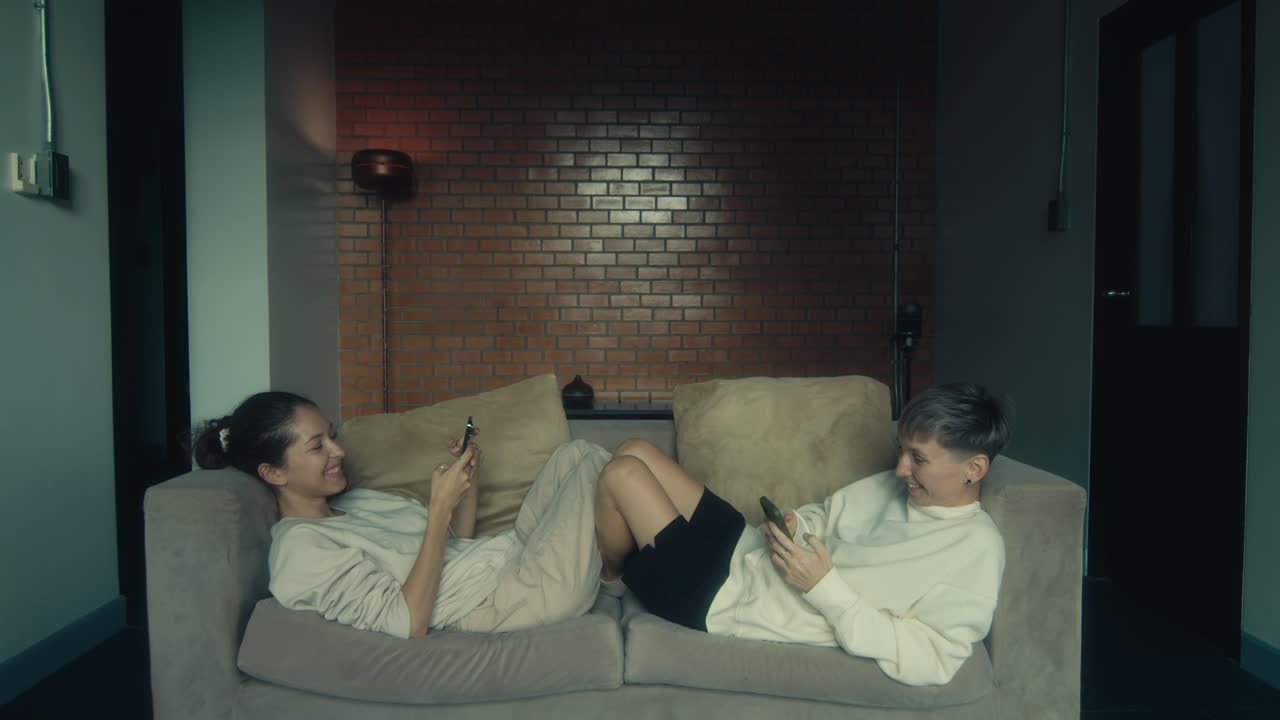 Two Women Relaxing on a Couch with Smartphones