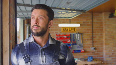 portrait of man wearing overalls in garage workshop at home