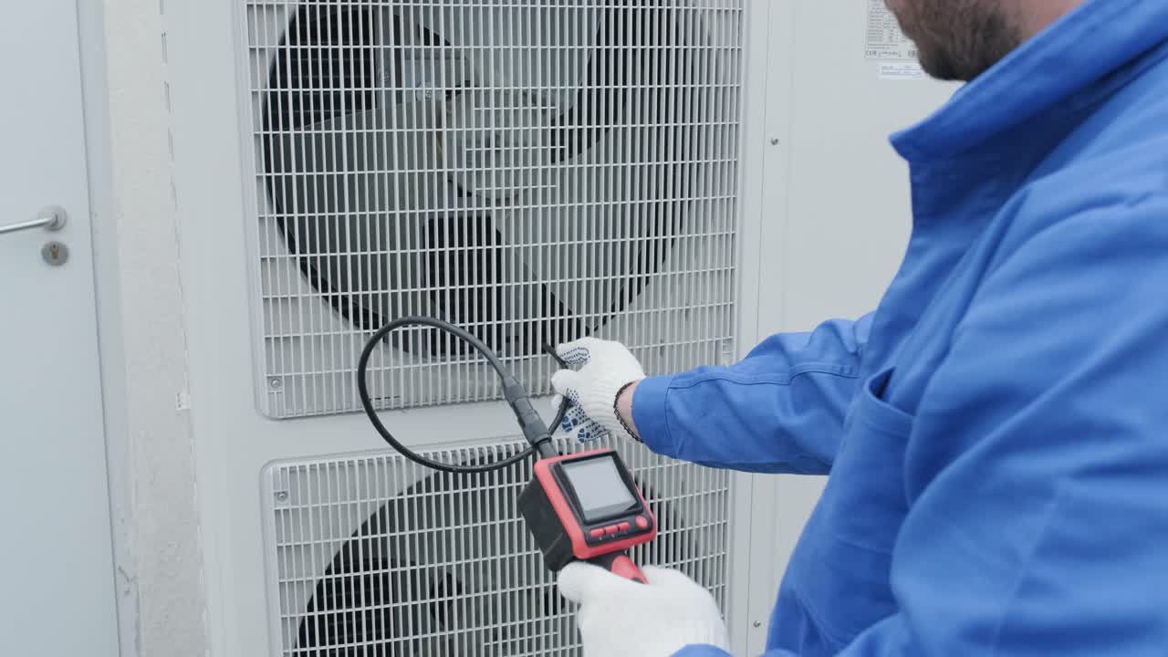 기술자는 디지털 카메라를 사용하여 열 교환기의 봉쇄를 확인합니다.