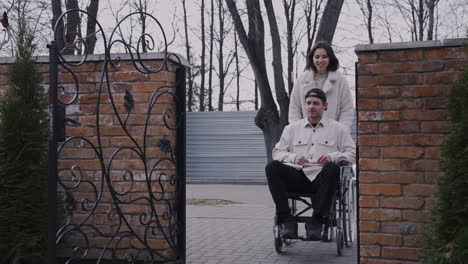 Young-Woman-And-Her-Disable-Friend-In-Wheelchair-Meeting-Other-Friends-In-A-Bar-Terrace