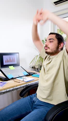 a man is sitting at a desk with a laptop and a computer monitor