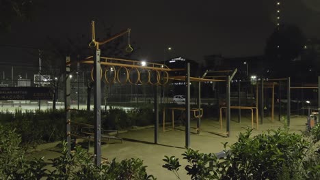 park area for sports and children. there are sports equipment and iron children's toys. at night.