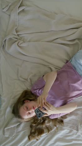 teenage girl lying in bed using smartphone