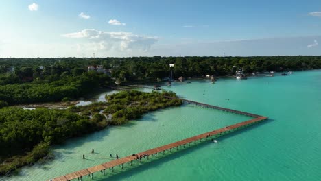 Gente-Caminando-En-Los-Muelles-En-El-área-Natural-Protegida-Parque-Laguna-De-Bacalar,-En-El-Soleado-México---Vista-Aérea