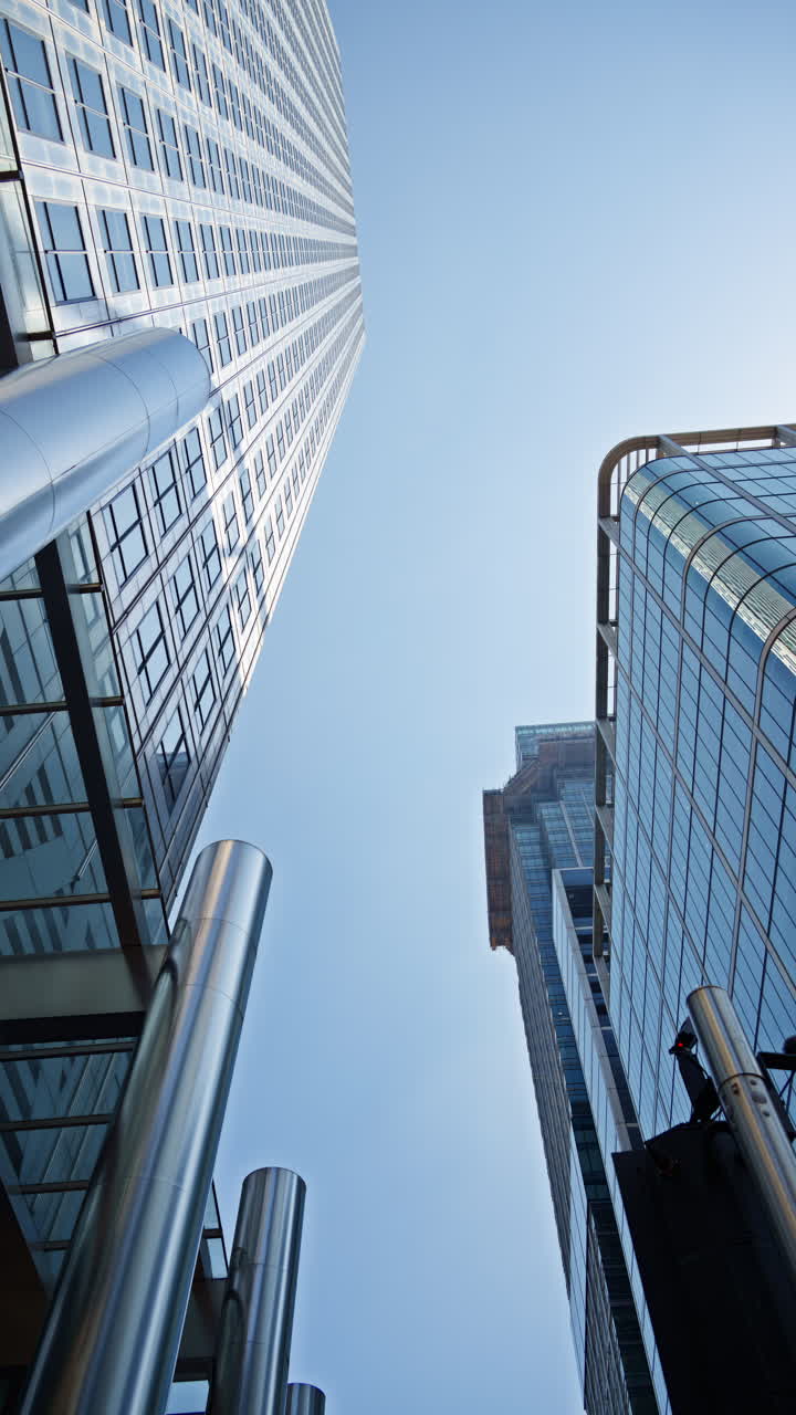 Low angle view of a modern glass One Canada Square office buildings in Canary Wharf, London, England in the evening. Vertical