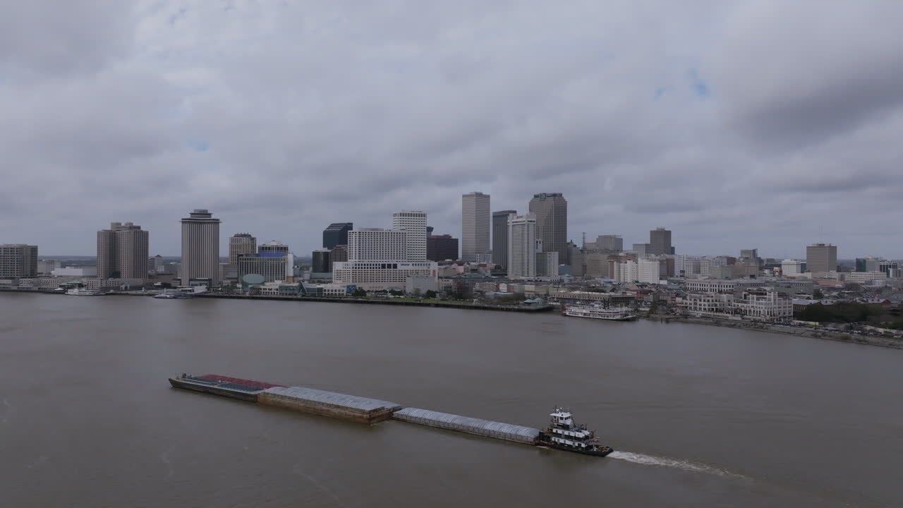 video aéreo estático de una gran barcaza que está navegando por el río mississippi con el centro de nueva orleans en el fondo