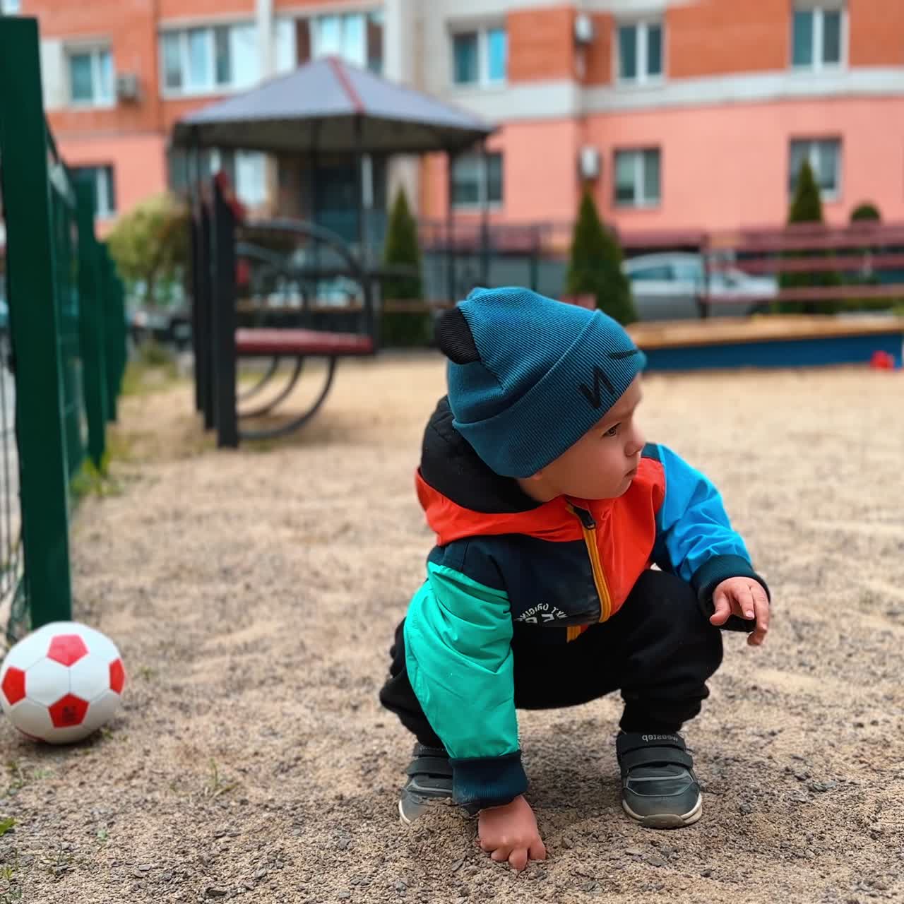 Playful boy is throwing sand on the playground. Baby studying the outer world