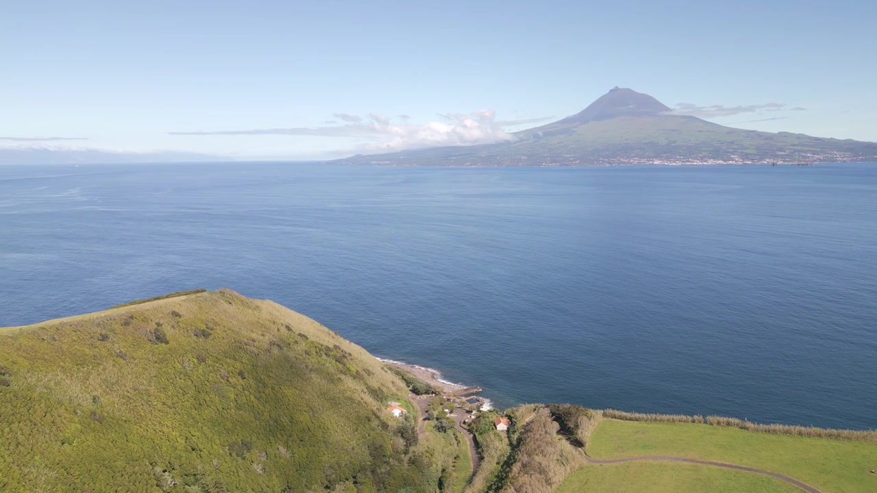 Riprese aeree cinematografiche da Faial nelle Azzorre che si affacciano sull'Oceano Atlantico verso l'isola di Pico, mostrando paesaggi vulcanici spettacolari, coste frastagliate e paesaggi naturali