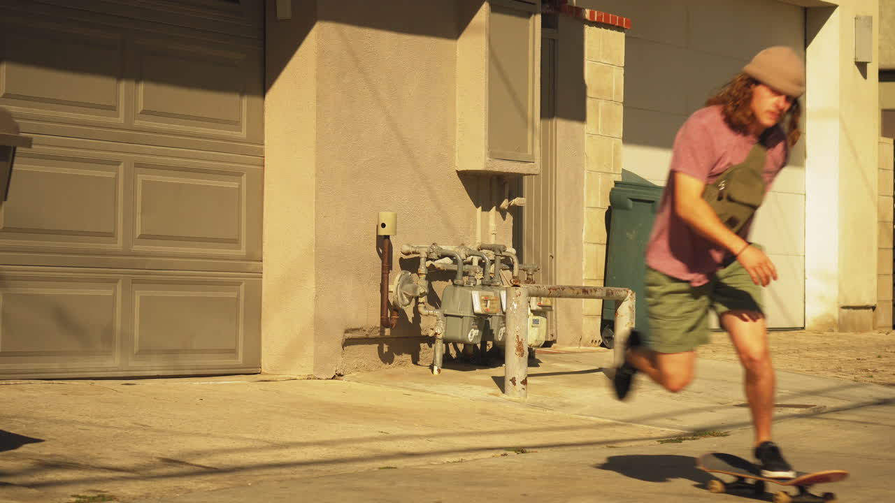 un adulto joven con el pelo rizado hace trucos de monopatín en viejas tuberías domésticas
