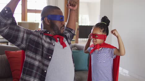 Happy-african-american-daughter-and-father-having-fun,-wearing-superhero-costumes