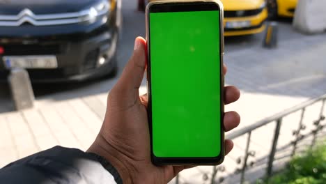 persona con un teléfono de pantalla verde en una calle de la ciudad