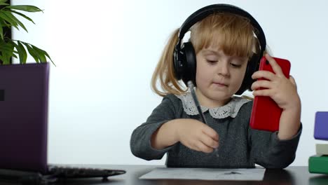 niño preescolar niña aprendizaje a distancia en línea en el hogar. niño estudiando usando teléfono móvil digital