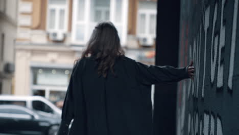 Urban-girl-walking-away-in-modern-city-building-near-road-with-cars.