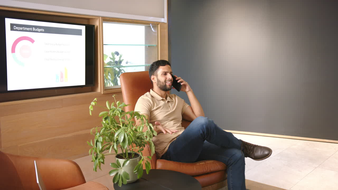 Talking on smartphone, man sitting in office chair with presentation on screen