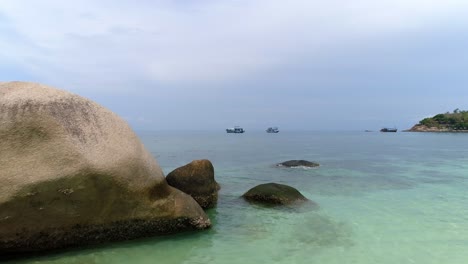 beautiful view of a tropical beach with clear turquoise water and boats in the distance