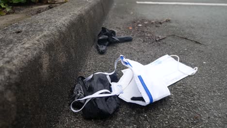 dirty discarded used corona virus masks and gloves pollution on street blowing in wind with copy space track left rising