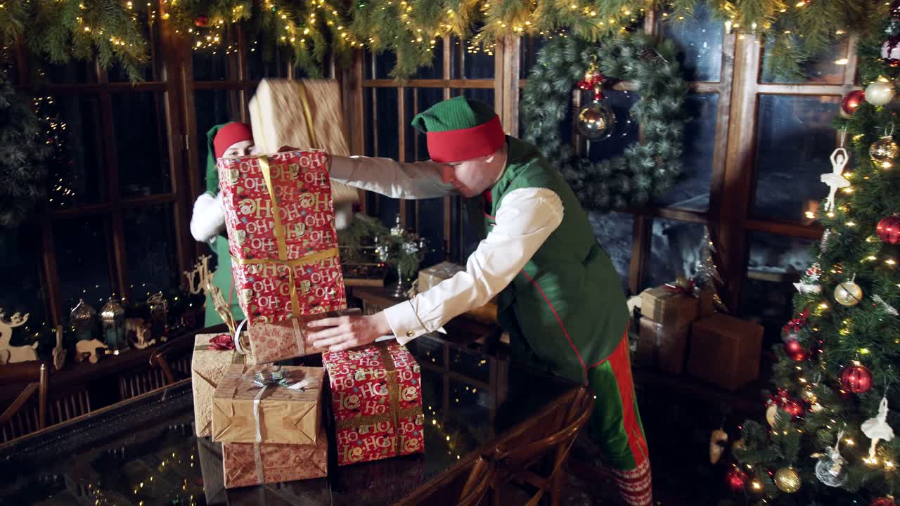 Christmas gifts in Santa's residence. Elves making a pile of gift boxes on the table in beautifully decorated room with Christmas tree