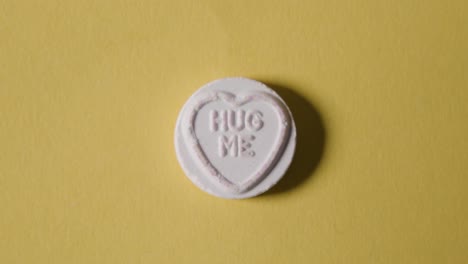 heart candy with hug me message on yellow background