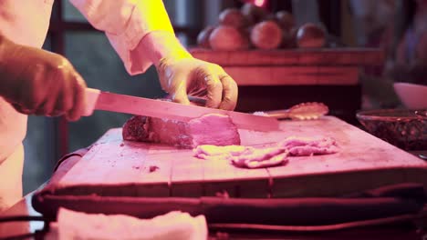 chef cortando un trozo de carne roja cocida con un cuchillo en el buffet