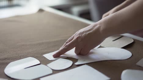 Female-dressmaker-uses-chalk-on-the-pattern-contour-on-textile,-in-atelier